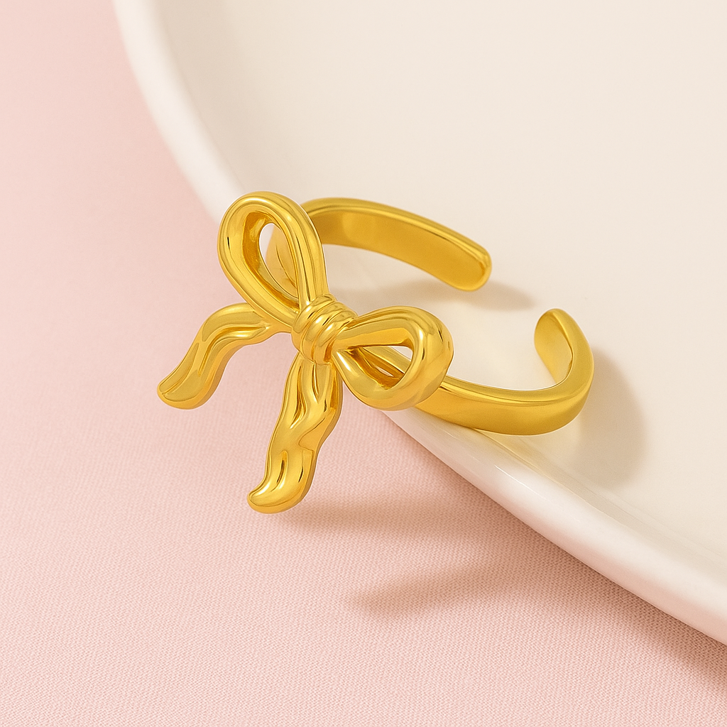 Gold bow-shaped ring on a pink background