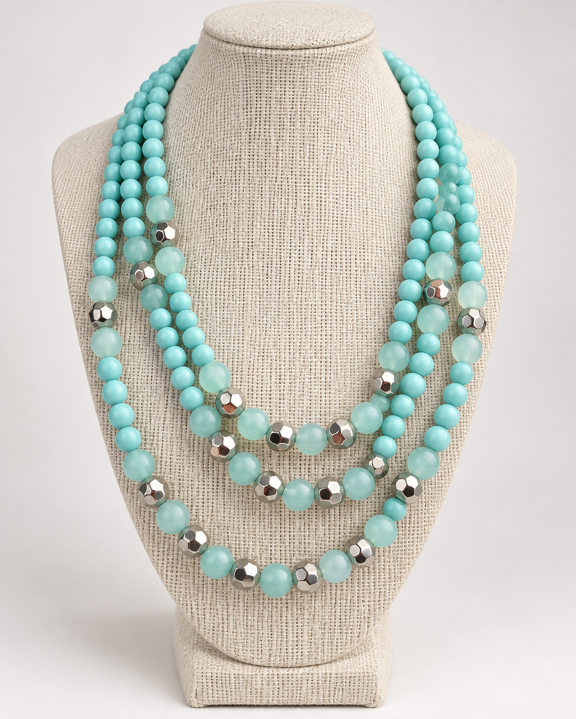 Close-up of pale aqua beads and faceted silver-tone accents on layered statement necklace