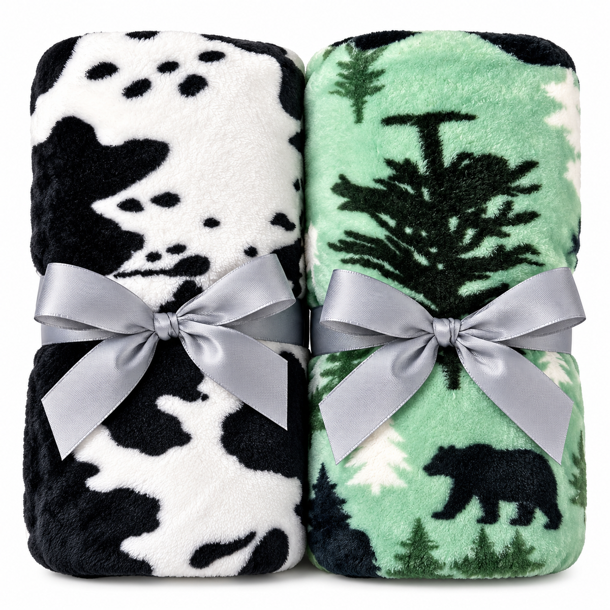 Two folded plush blankets tied with silver bows, shown side by side on a white background. The left blanket has a black and white cow print, and the right blanket has a green forest pattern with a bear and trees.