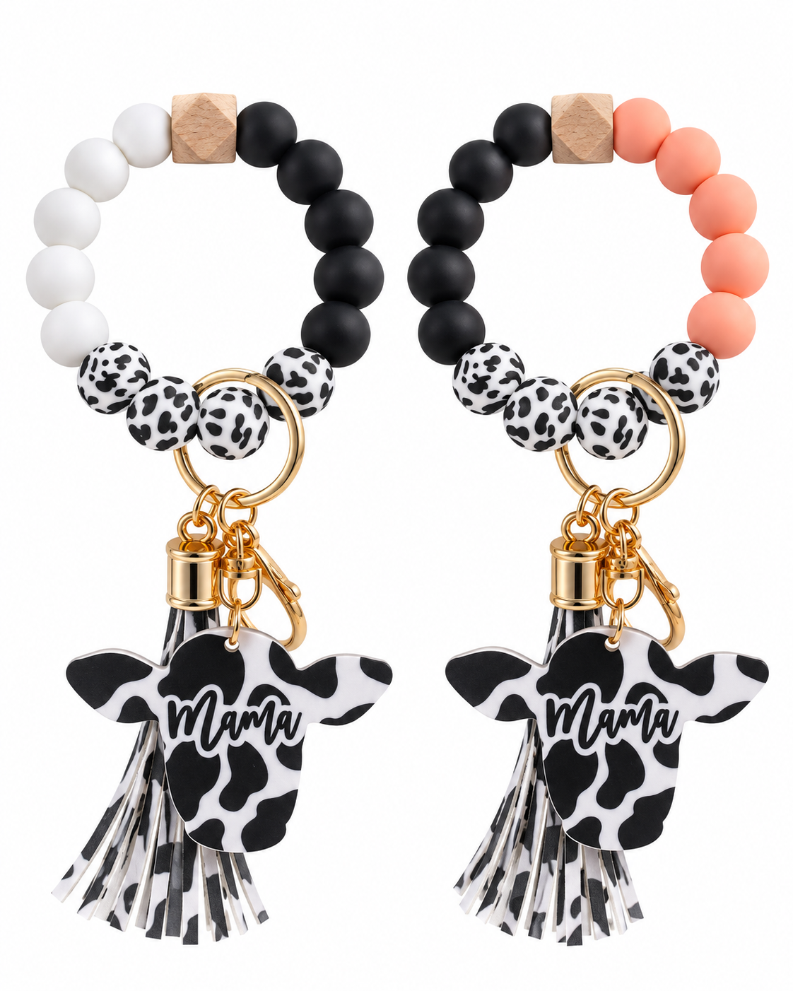 Two beaded keychains with cow-print tassels and 'Mama' text charms, displayed side by side on a white background. One keychain features white and black beads, and the other features peach and black beads.