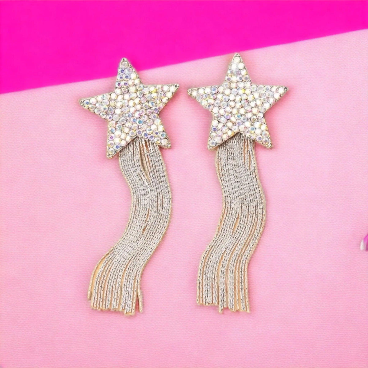 Star-shaped earrings with tassels on a pink background