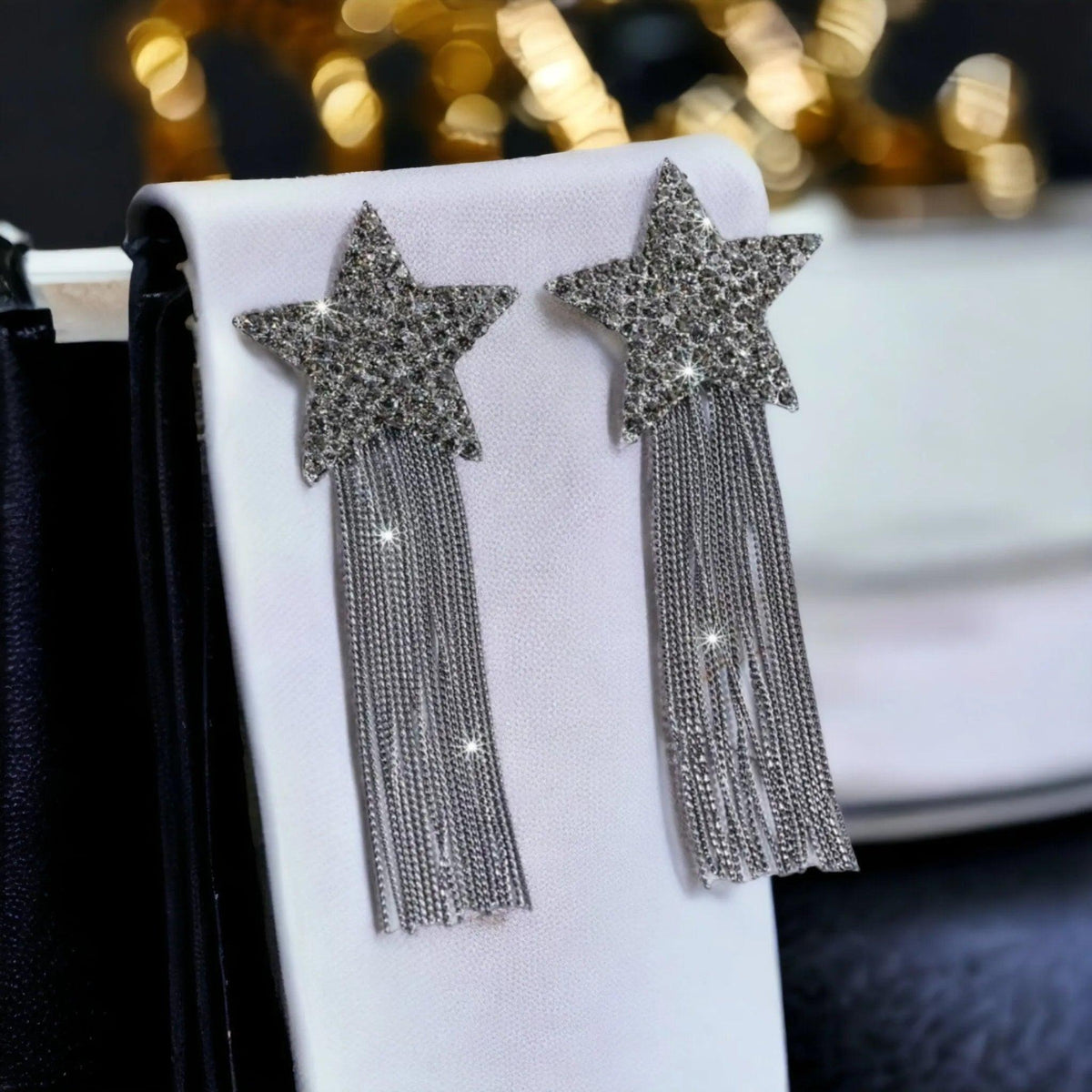 Star-shaped earrings with tassels on a white surface with a blurred background