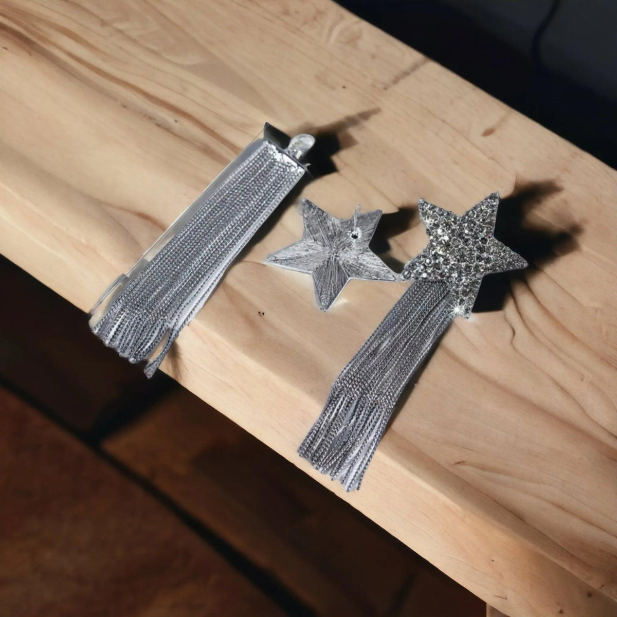 Silver star-shaped earrings with tassels on a wooden surface