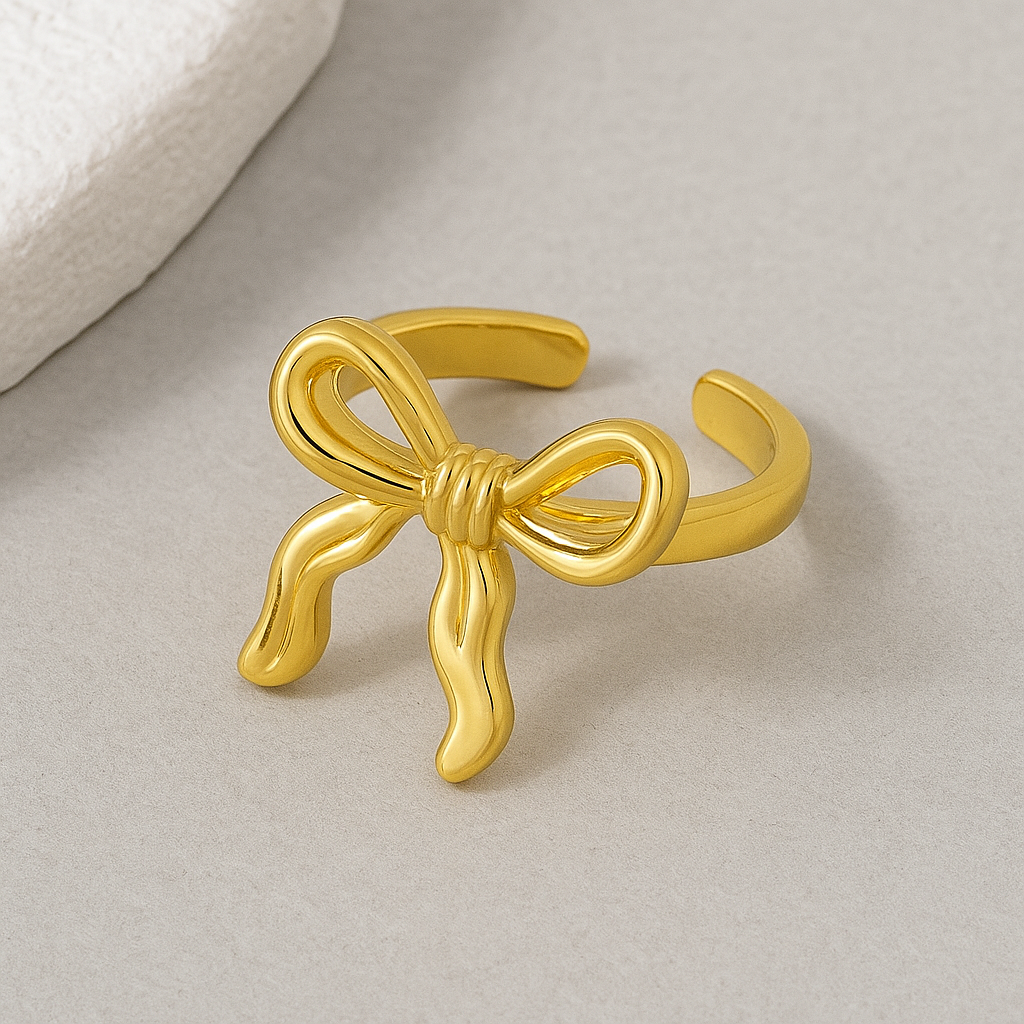 Gold bow-shaped ring on a light gray background