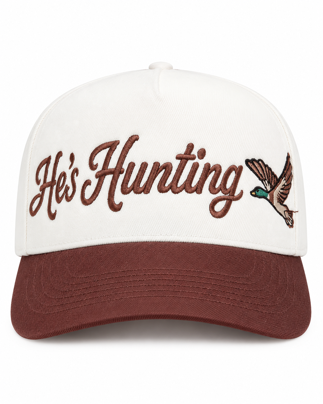 A baseball cap with an off-white crown and a dark brown curved brim. The front features the embroidered text 'He's Hunting' in brown cursive script alongside an embroidered brown, green, and beige bird.