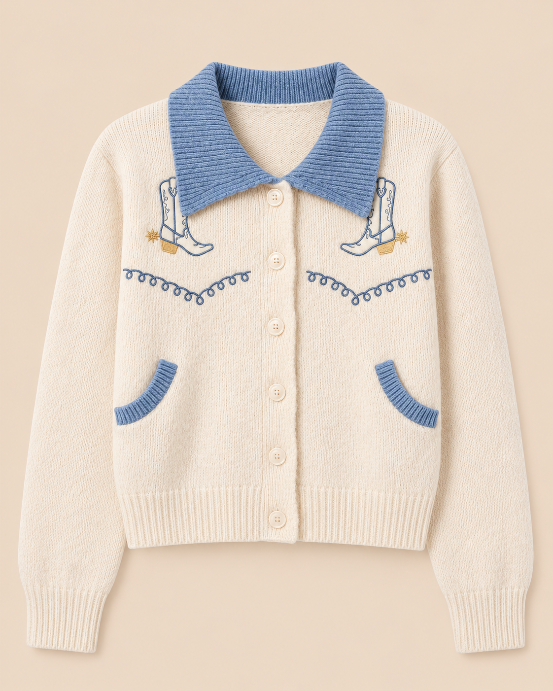 An off-white knit cardigan sweater with a light blue collar, blue pocket trim, and embroidered cowboy boots and wavy line details on the front, shown against a solid beige background.