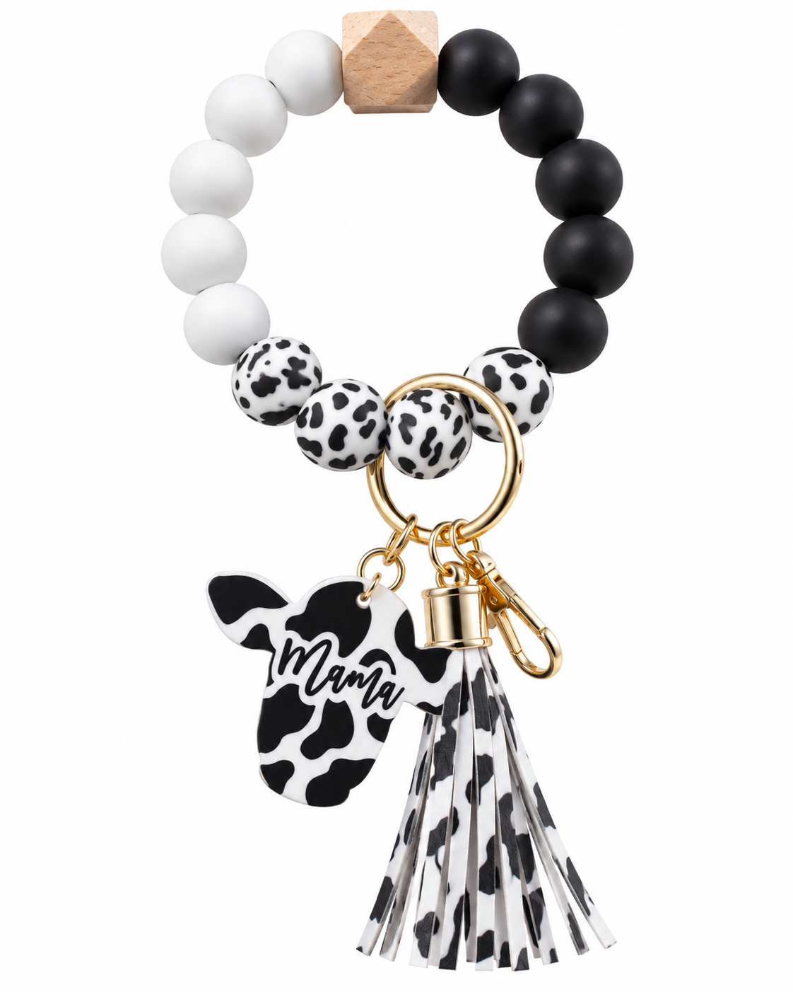 A beaded keychain bracelet with white and black matte beads, cow-print patterned beads, a wooden accent, a gold-tone keyring, a cow-shaped charm with the name 'Mamy', and a black-and-white cow-print tassel, shown on a plain white background.