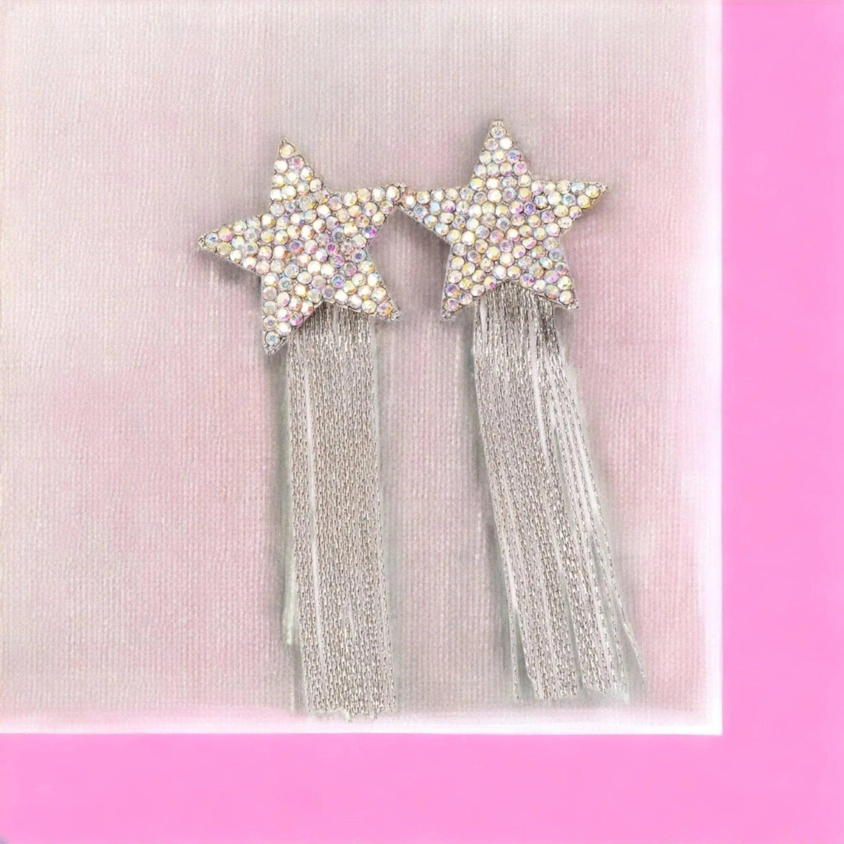 Star-shaped hair accessories with tassels on a pink background