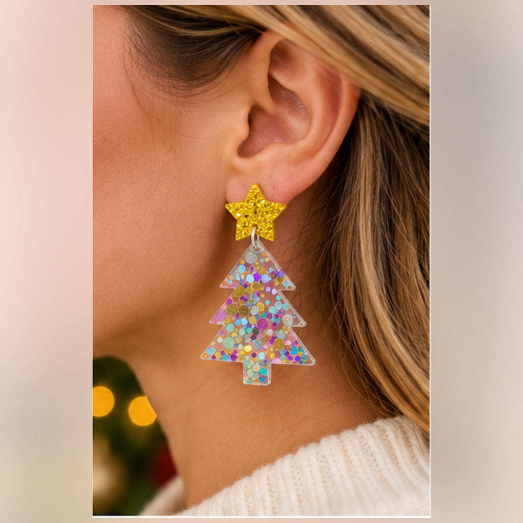 A close-up of a person's ear wearing a dangling earring with a glittery gold star and a glittery iridescent Christmas tree charm.