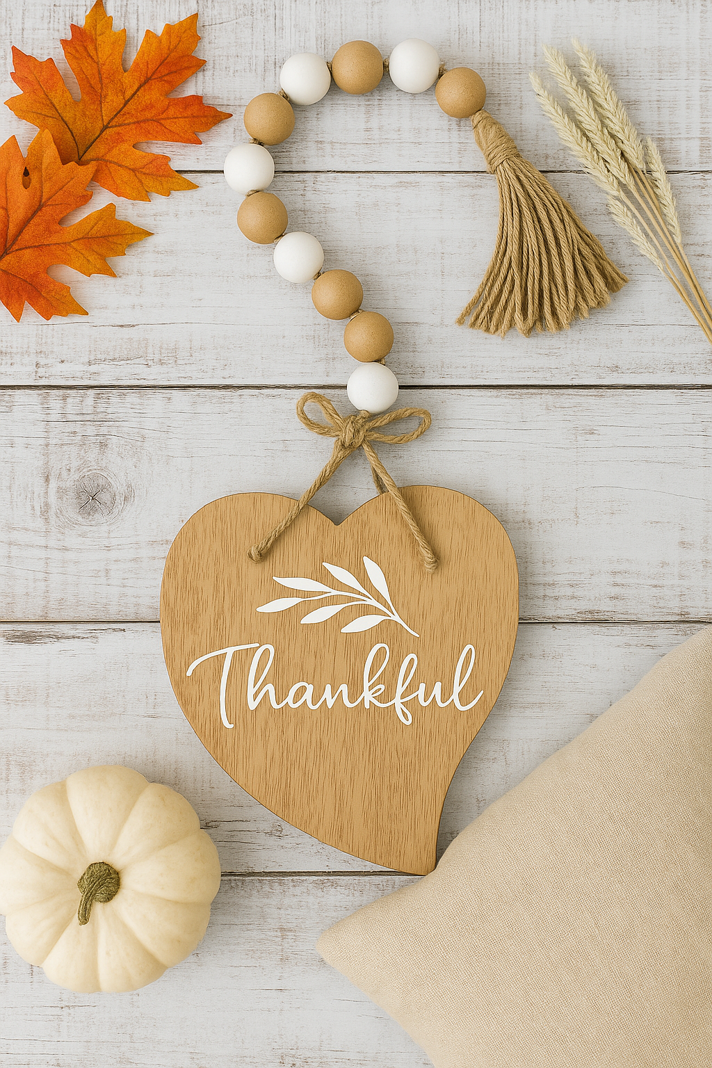 Wooden heart-shaped sign with 'Thankful' text, surrounded by autumn decorations on a wooden surface.